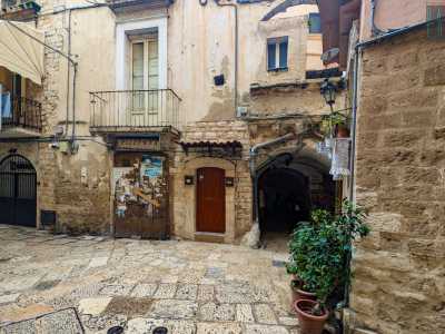 Restiamo nel centro storico per dirigerci verso la Basilica di San Nicola. Imbocchiamo la strada denominata piazza 62 Marinai e, accanto a Corte Garritta...